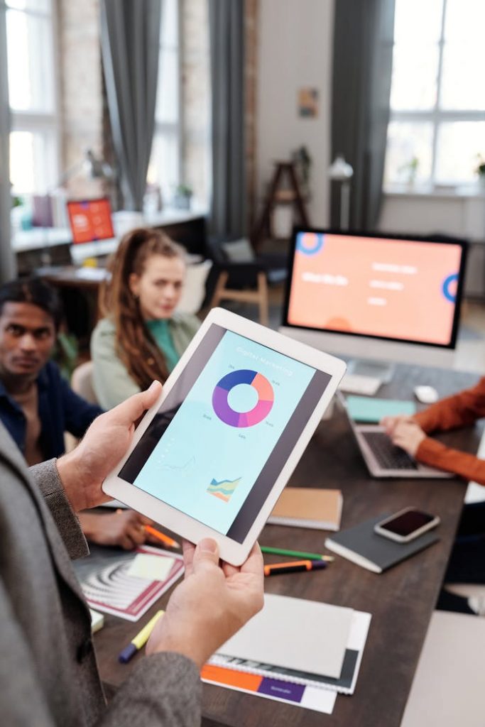 Colleagues reviewing business data on a tablet in a modern office setting.